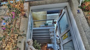 A narrow entrance with a statue of a child and a baby carriage, a small balcony with a purple awning, and a sign reading "LEYLA SUITE".