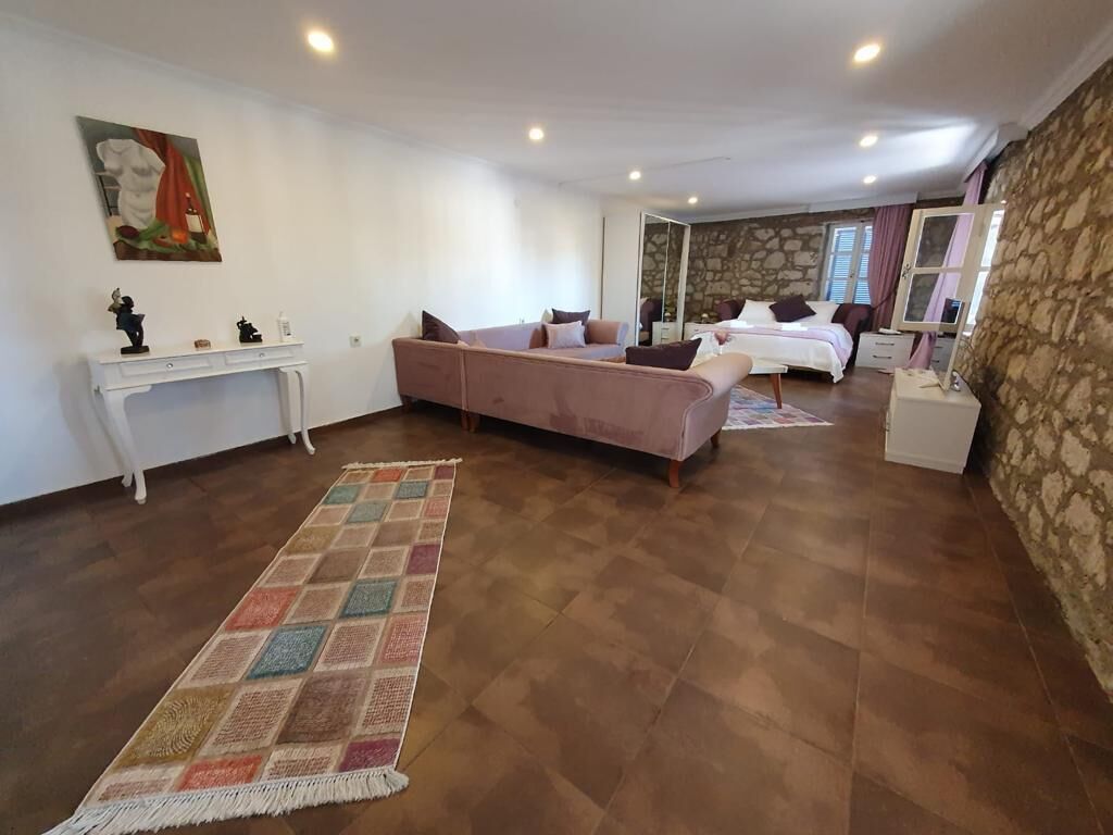 Une pièce spacieuse avec un grand canapé, un lit, une petite table et un miroir.