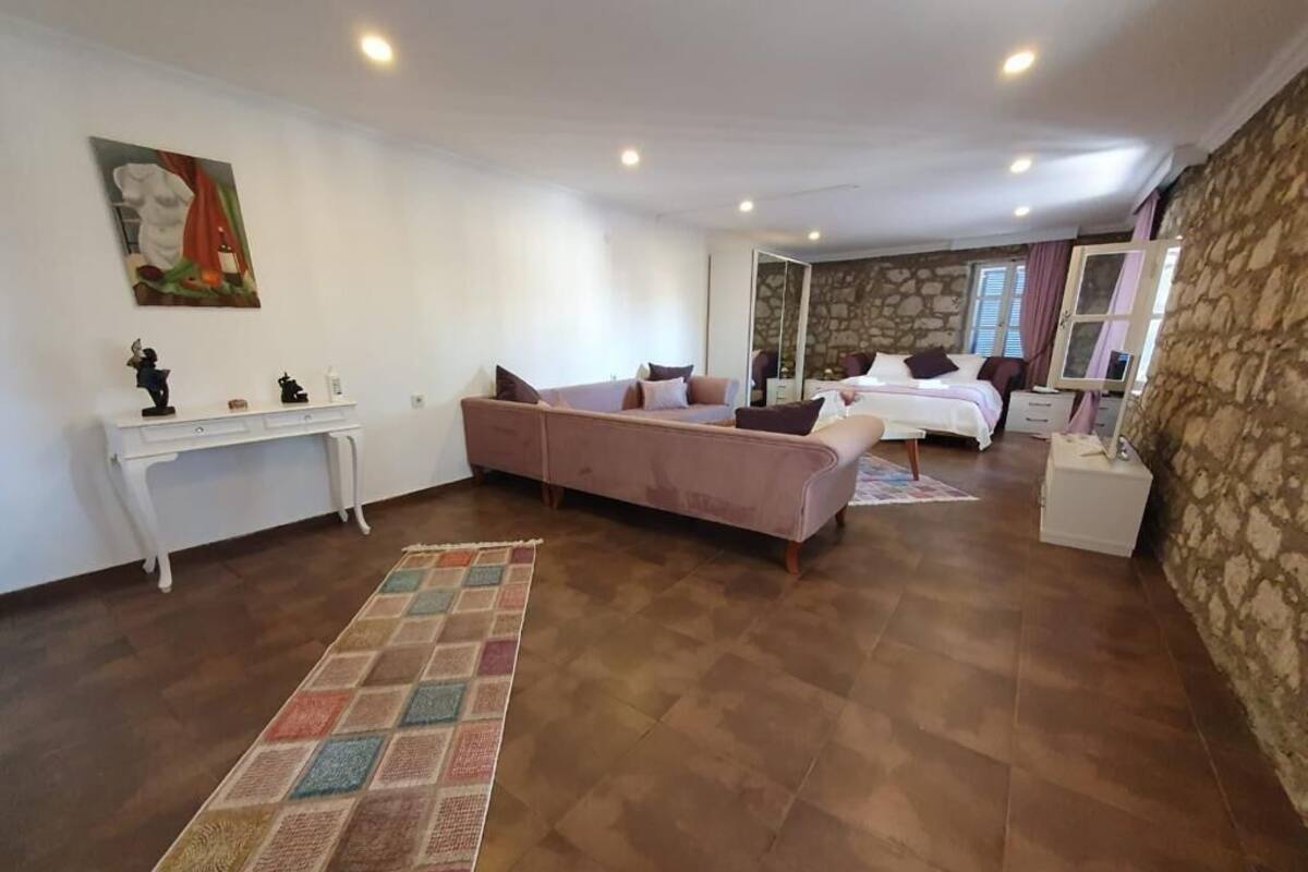 A spacious room with a large sofa, a bed, a small table, and a mirror.
