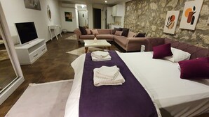 Una habitación de hotel con cama, sofá, televisión y obras de arte en las paredes.
