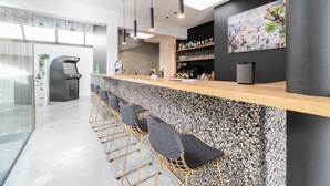 A modern bar area with a granite countertop, bar stools, and a large painting on the wall.