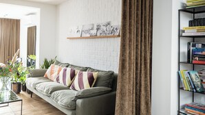 A modern living room with a grey sofa, a wooden coffee table, and a bookshelf.