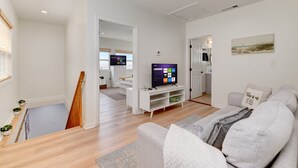 A modern living room with a flat-screen TV, a grey sofa, and a wooden staircase. - Cozy 3BR Renovated Home with Scenic Views! Near Downtown/Airport/Gaslamp Quarter (San Diego)