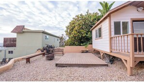 Una propiedad residencial con un patio, una pequeña terraza y un árbol grande.