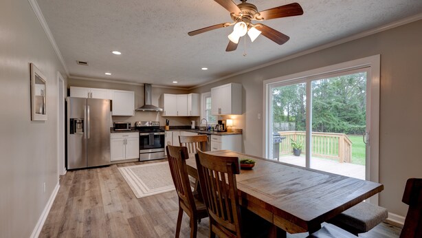 A modern kitchen with white cabinets, stainless steel appliances, and a wooden dining table with chairs.