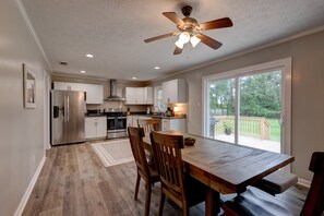 A modern kitchen with white cabinets, stainless steel appliances, and a wooden dining table with chairs.