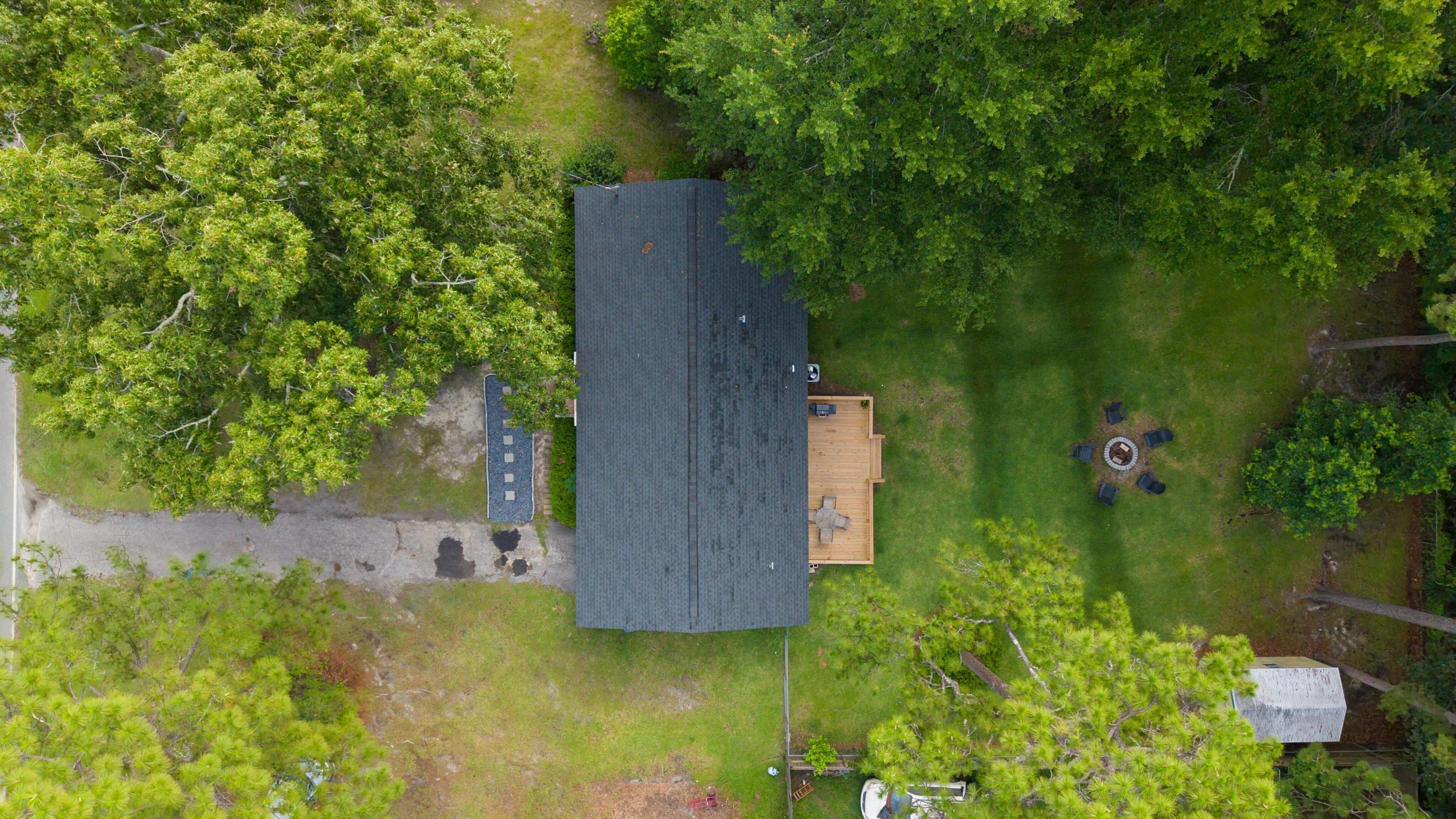 Vue aérienne d’une maison au toit sombre, entourée d’arbres verdoyants.