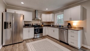 A modern kitchen with stainless steel appliances, white cabinetry, and a granite countertop.
