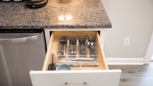 A kitchen drawer with utensils and a coffee maker on the countertop.