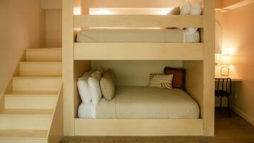 Una cama litera con escritorio y silla en una habitación con escaleras de madera.