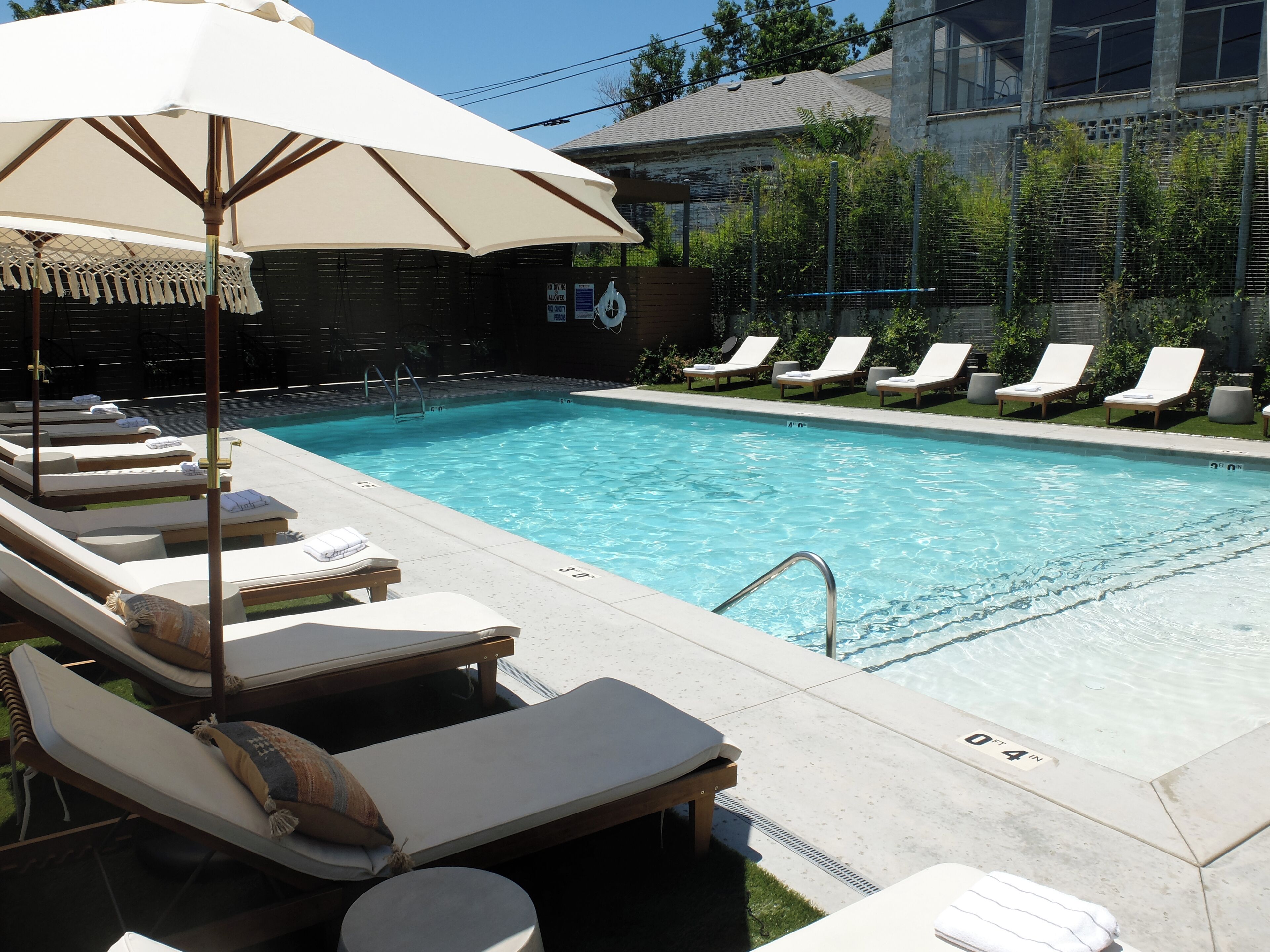 Una piscina con sillones de descanso y una sombrilla.