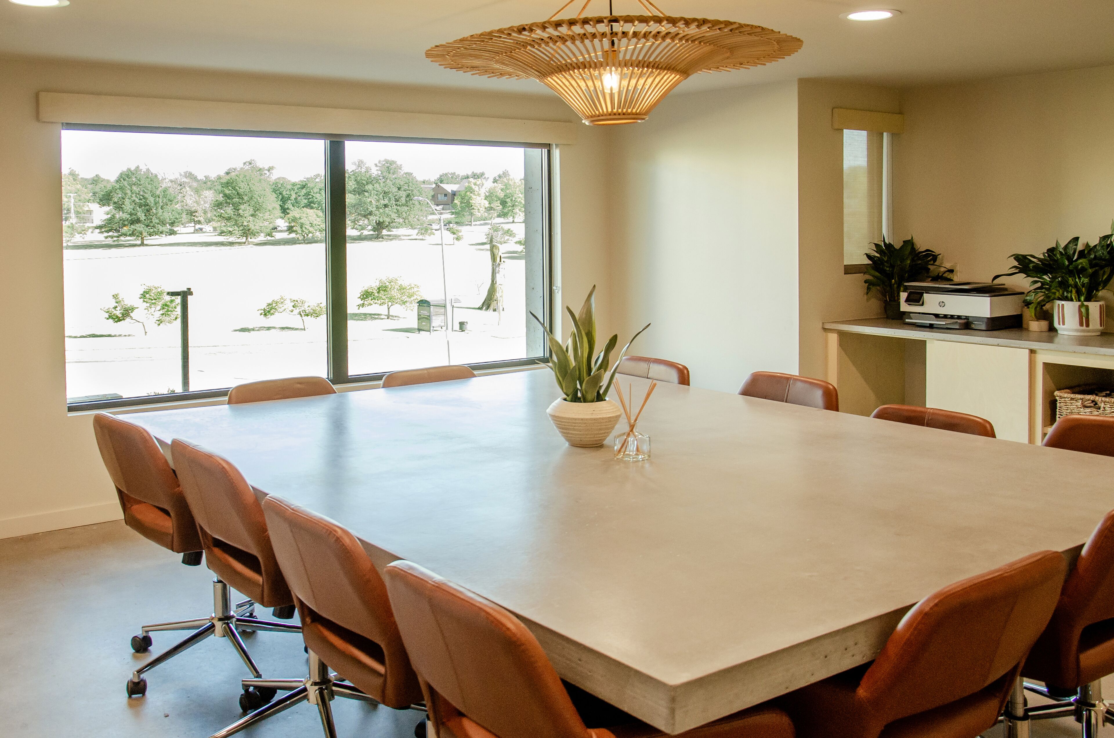 A conference room with a large table, chairs, and a view through the windows.
