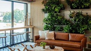 A modern living room with a brown leather sofa, a wooden coffee table, and a large window. - Brut Hotel (Tulsa)