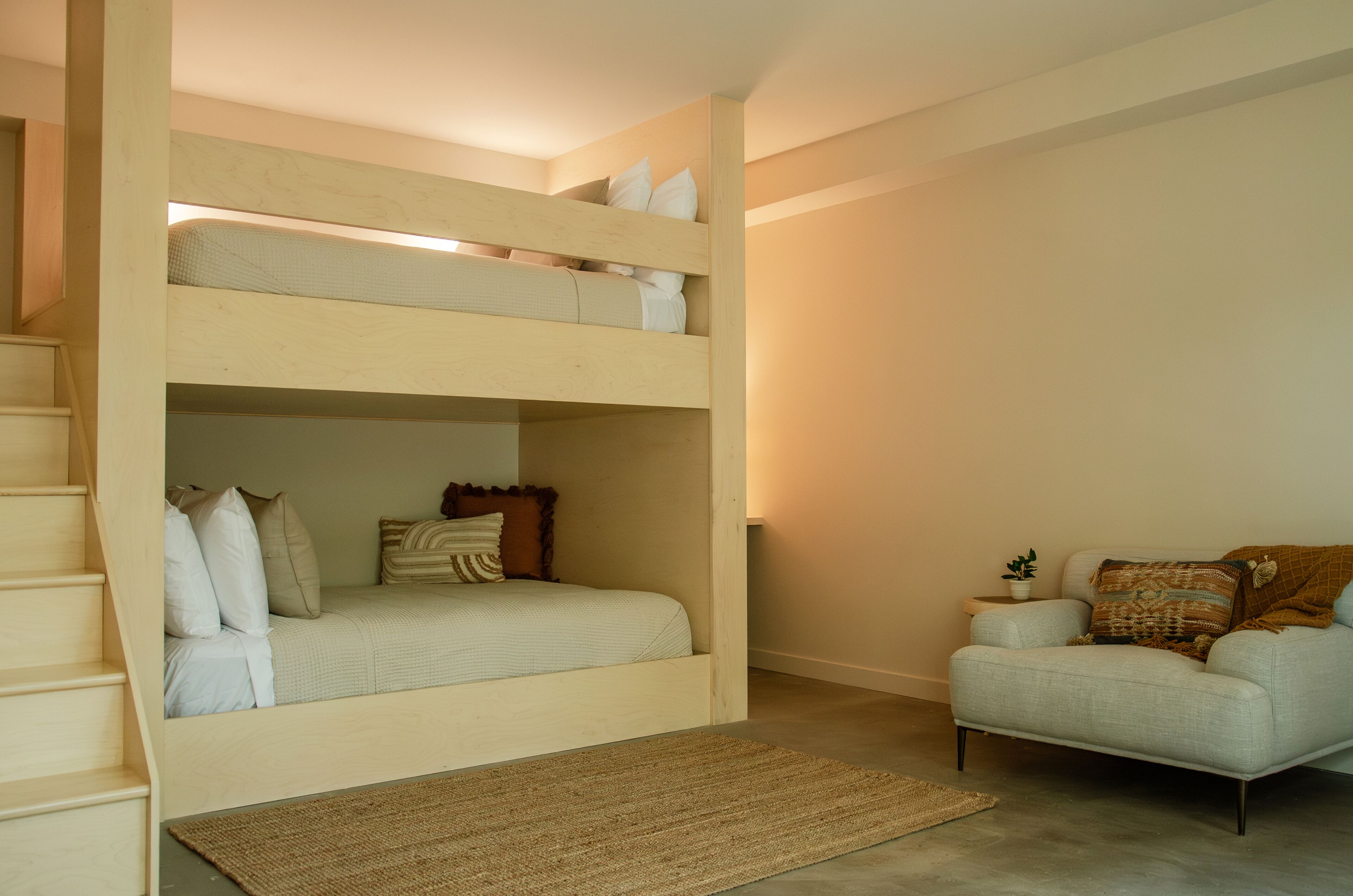 A bunk bed with a sofa and a small table in a room with a carpet.