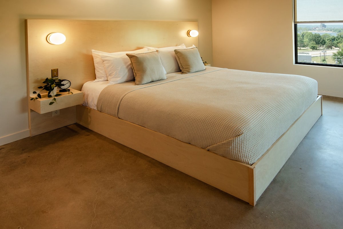 A modern bedroom with a large bed, two bedside tables, and a view of the outdoors.