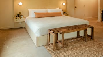 A bedroom with a bed, bedside tables, a wooden bench, and a textured rug.