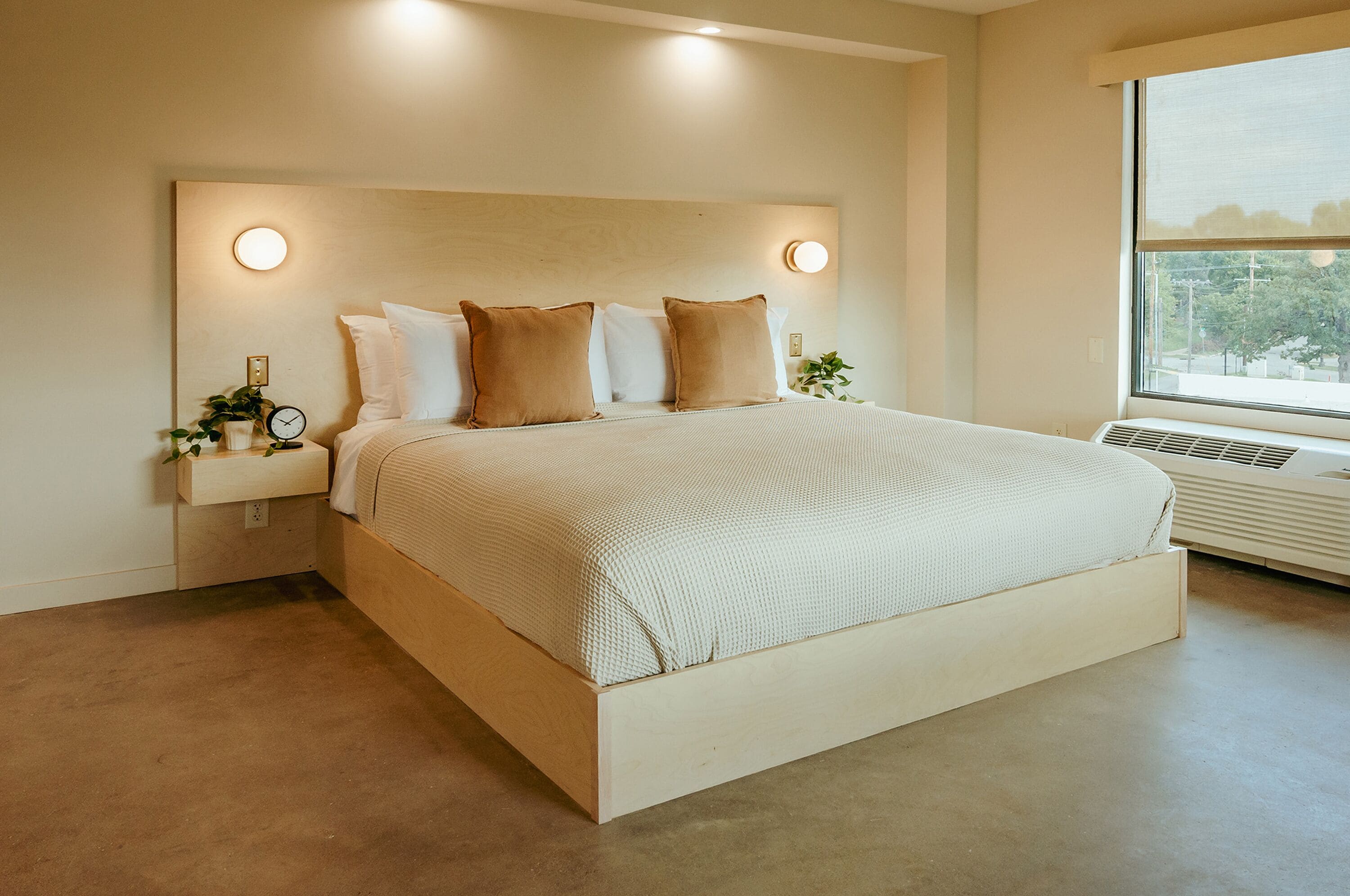 Un dormitorio moderno con una cama grande, lámparas de noche y una ventana con vistas.