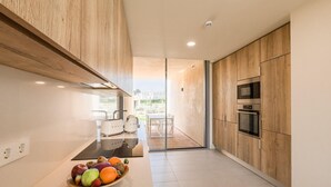 Una cucina moderna con mobili in legno, forno integrato e una ciotola di frutta sul piano di lavoro.