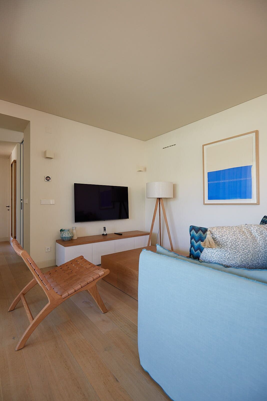 Un salon moderne avec un téléviseur à écran plat, une lampe sur pied, un canapé et une table basse en bois.