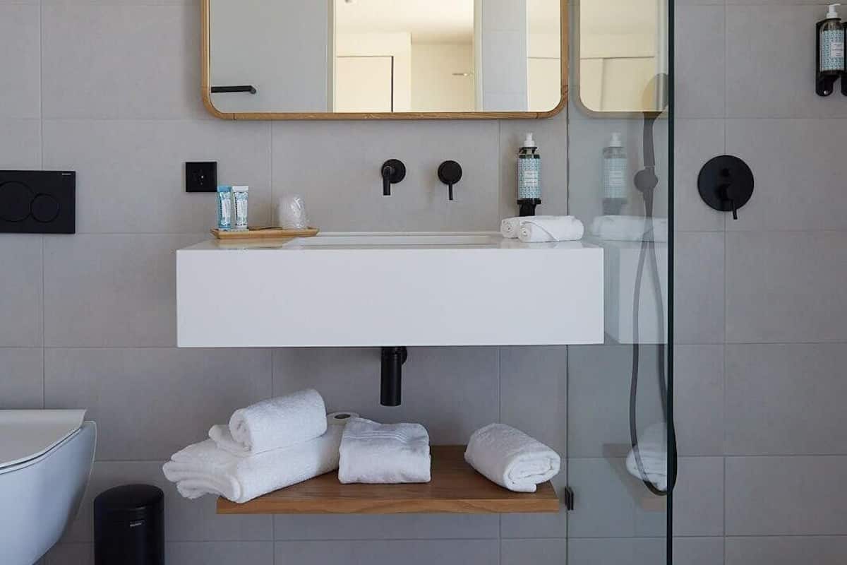 A modern bathroom with a large mirror, white sink, and a glass shower enclosure.
