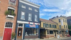 A row of buildings with a storefront named "Rude Betty" featuring a blue awning and a red door.