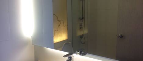 A bathroom with a white sink, a mirror, and a glass-enclosed shower.