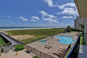 Un espace piscine sur le toit, comprenant plusieurs piscines, avec vue sur la plage et un bâtiment en arrière-plan.