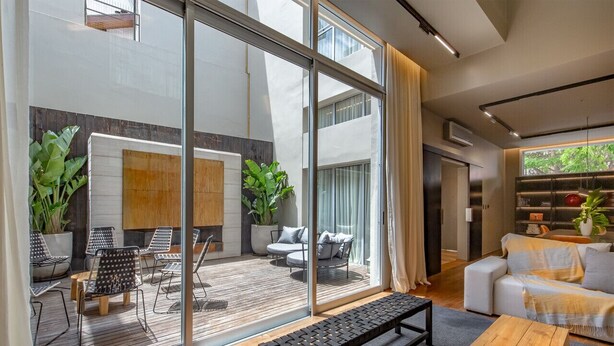 Un salon moderne doté d’une grande porte vitrée donnant sur un patio extérieur.