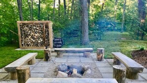 A fire pit area with benches and a stack of firewood. - Stunning Modern Beach / Ski House (Tiny)