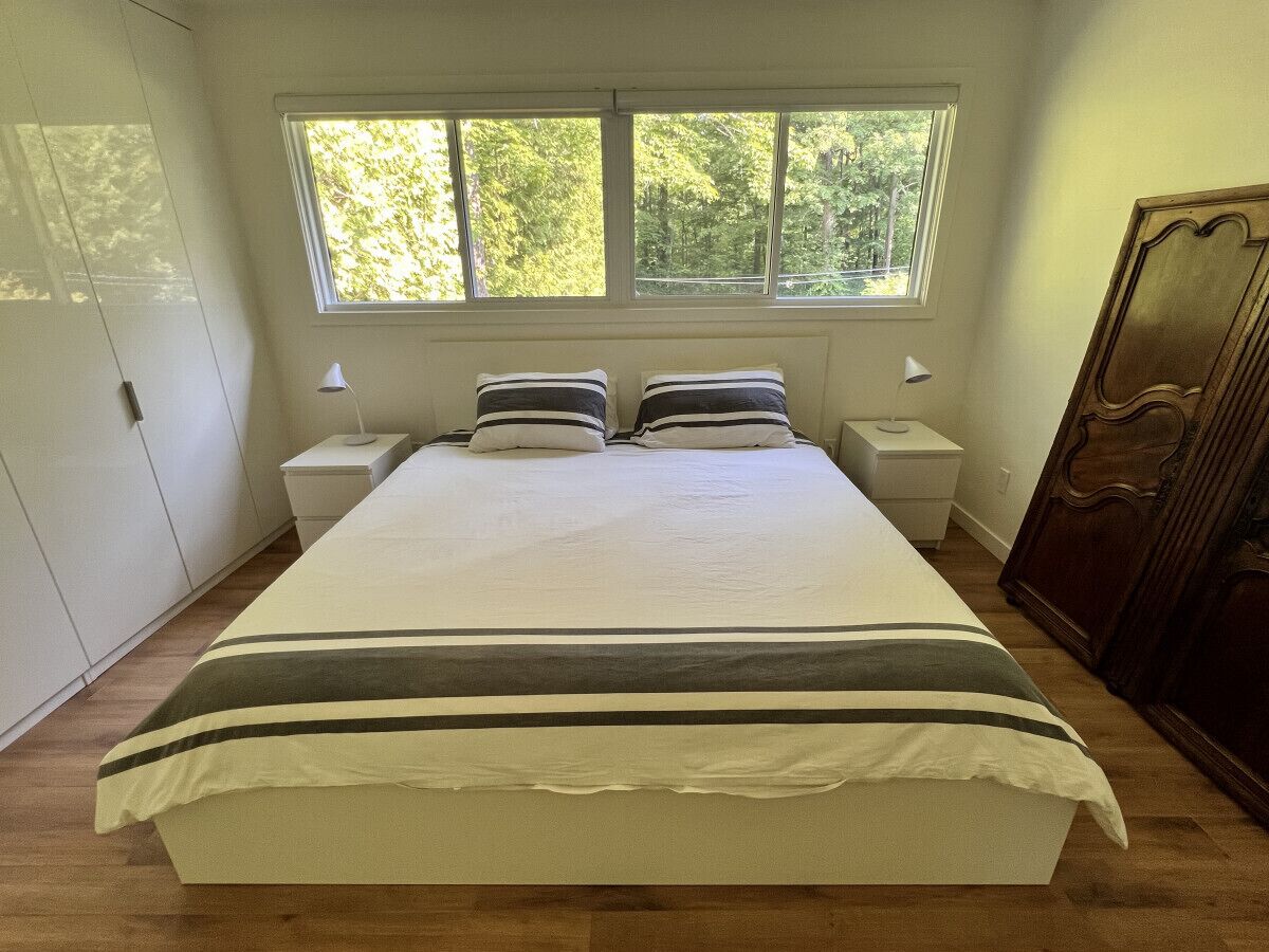 Ein Schlafzimmer mit einem großen Bett, zwei Nachttischen, einem Fenster und einem Kleiderschrank.