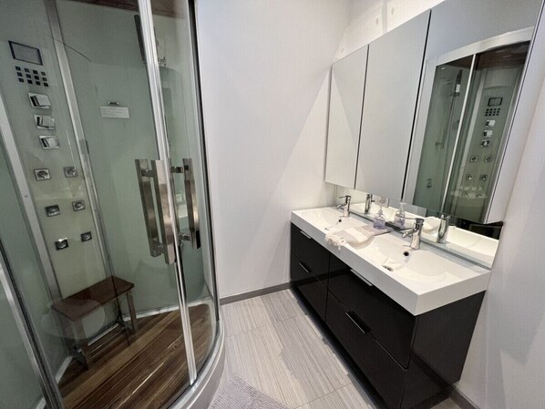 A modern bathroom with a glass shower enclosure, a double sink vanity, and a large mirror. - Stunning Modern Beach / Ski House (Tiny)