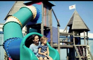 Explore the fun of a green spiral slide and a charming playhouse with a flag.