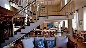 Un intérieur spacieux comprenant un escalier, un coin salon avec des coussins et un bar.