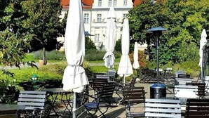 Une terrasse extérieure avec des tables et des chaises, des parasols, et un bâtiment en arrière-plan.