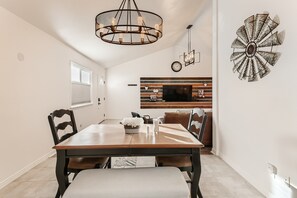 Enjoy meals in this stylish dining area with a wooden table, comfortable chairs, and a wall-mounted TV.