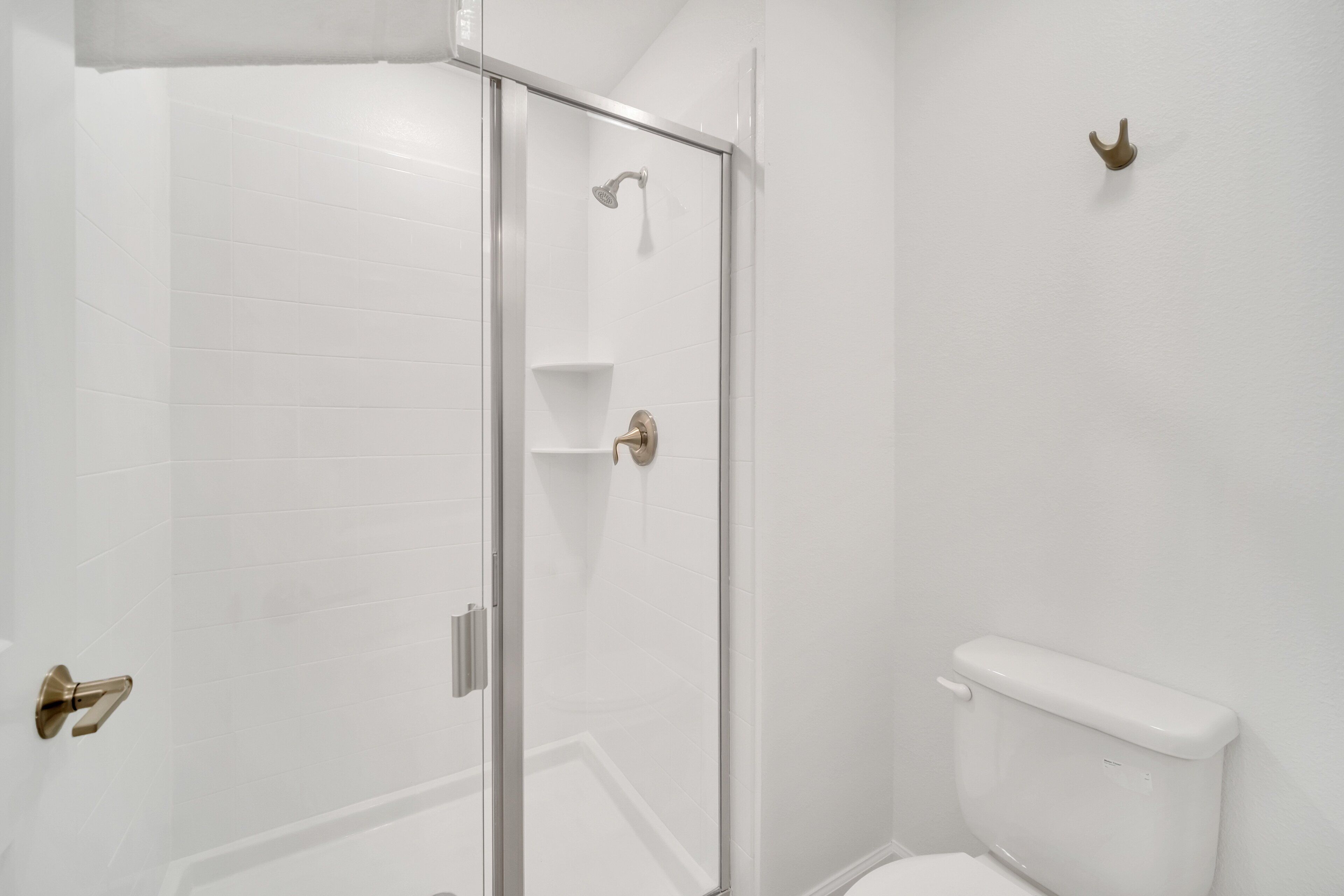 A bathroom with a glass shower enclosure, a toilet, and a wall-mounted towel rack.