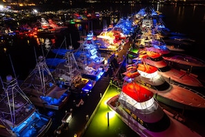 A marina with multiple boats docked, some with covered areas and others open.