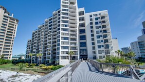 A modern hotel with multiple floors, a wooden deck, and a pool area. - Book 3 Nights & Get 1 Free-See Description* Beachfront*Tram* Pool *Stunning View (Miramar Beach)