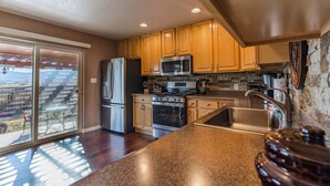 A kitchen with wooden cabinets, stainless steel appliances, a granite countertop, and a sliding glass door leading to a patio. - Beautiful Warm and Spacious Home, 3bed/2 full bath (Cañon City)