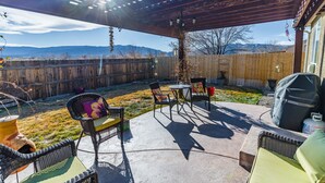 A covered patio with outdoor furniture, a grill, and a view of mountains. - Beautiful Warm and Spacious Home, 3bed/2 full bath (Cañon City)