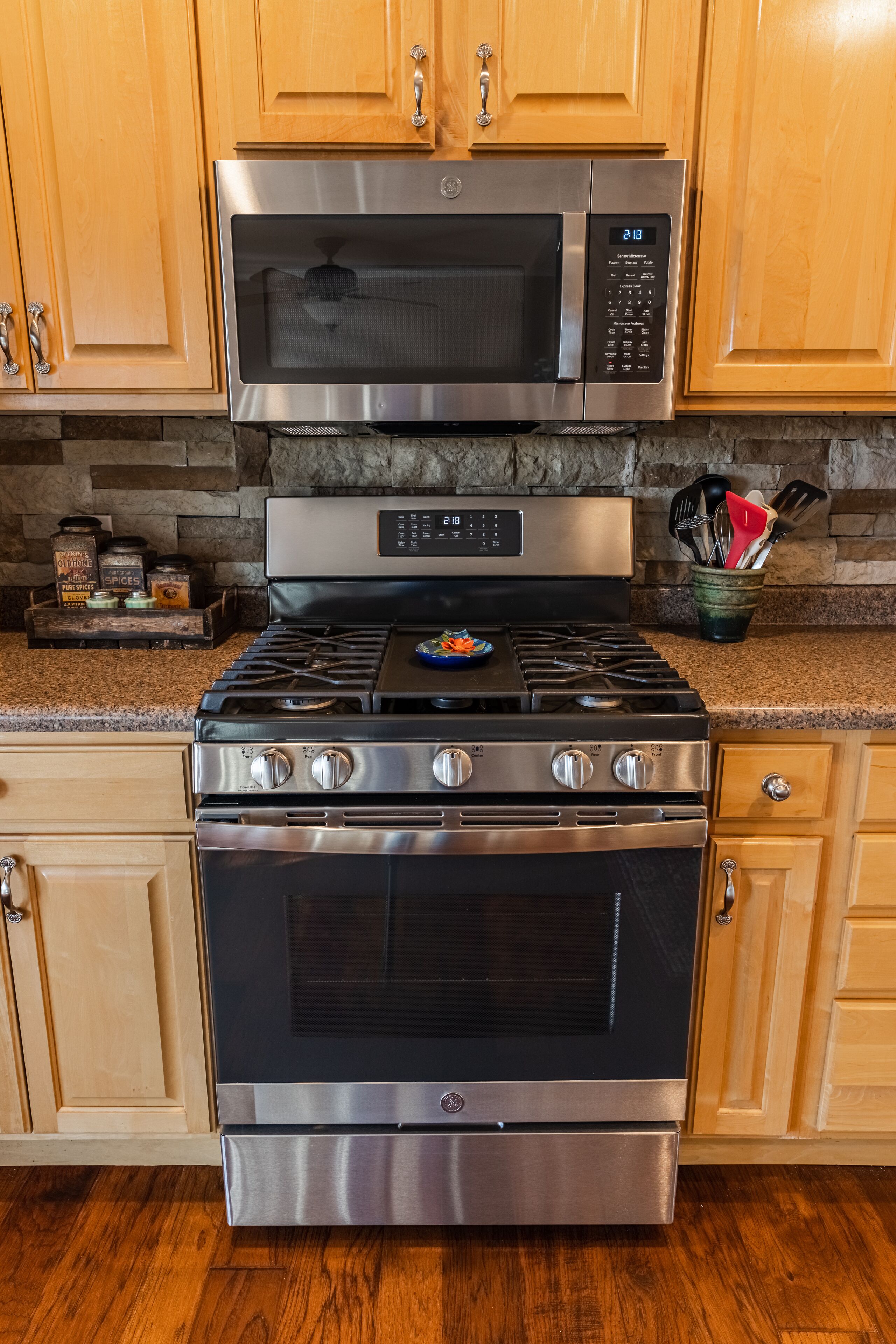 A kitchen with a stainless steel range hood, oven, and microwave.