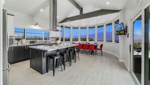 Een moderne keuken met een groot schiereiland, barkrukken en een eethoek met rode stoelen.
