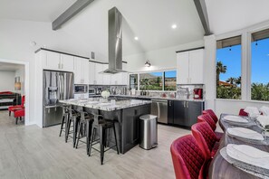 A modern kitchen with a central island, stainless steel appliances, and a view of the outdoors. - Newly Renovated - Breathtaking Views - POOL / SPA (Desert Hot Springs)