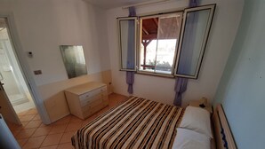 A bedroom with a bed, a dresser, a mirror, and a window.