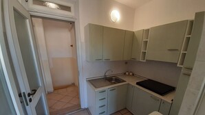 A compact kitchen with a sink, countertop, and light green cabinets.