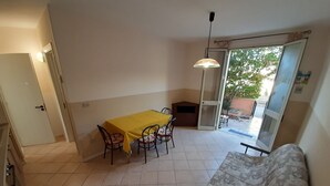 Ein Zimmer mit Esstisch, Stühlen, einer Couch und einer Glasschiebetür zu einem Außenbereich.