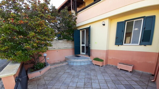 A courtyard with tiled flooring, a small staircase leading to a door, and a potted plant. - Red House Pescoluse (Marina di Pescoluse)