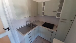 A compact kitchen with white cabinets, a sink, and a black countertop. - Red House Pescoluse (Marina di Pescoluse)