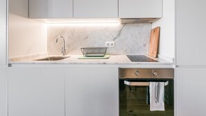 A modern kitchen with a built-in sink, a dish rack, a stove, and an oven. - GuestReady - One Step Closer (Porto)