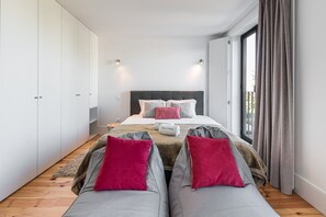 Ein modernes Schlafzimmer mit einem großen Bett, zwei Nachttischen, einem Kleiderschrank und Blick durch ein großes Fenster.